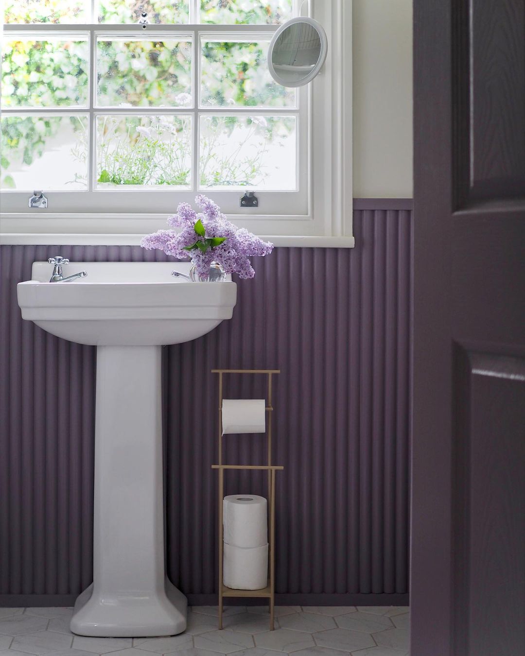 Cuarto de baño con revestimiento morado en la pared y puerta a juego.