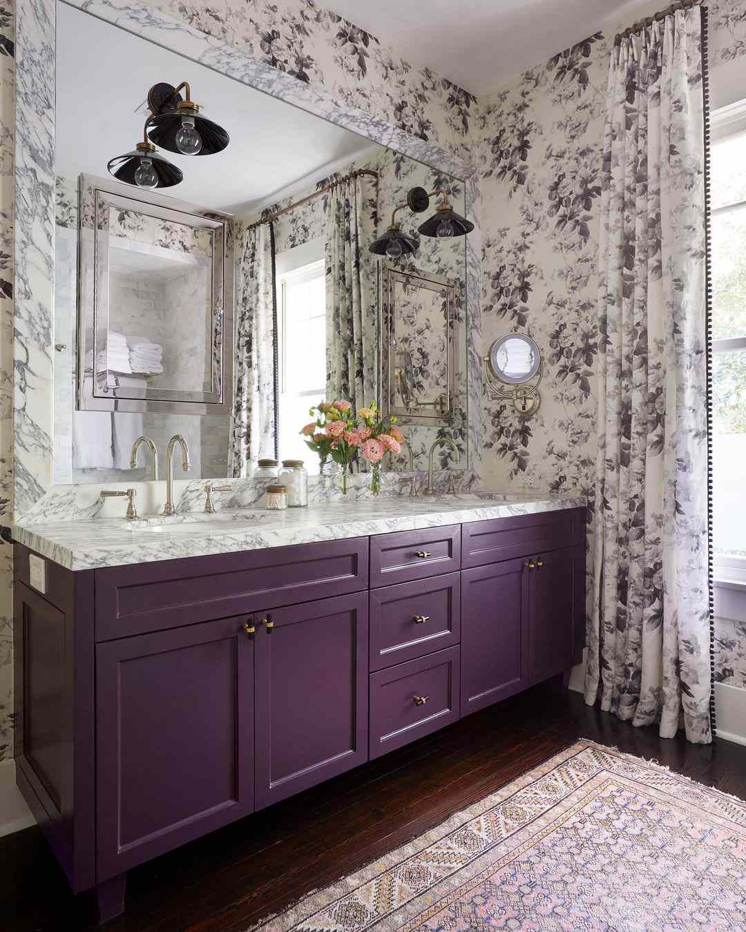 Salle de bain avec vanité violette et papier peint et rideaux assortis.