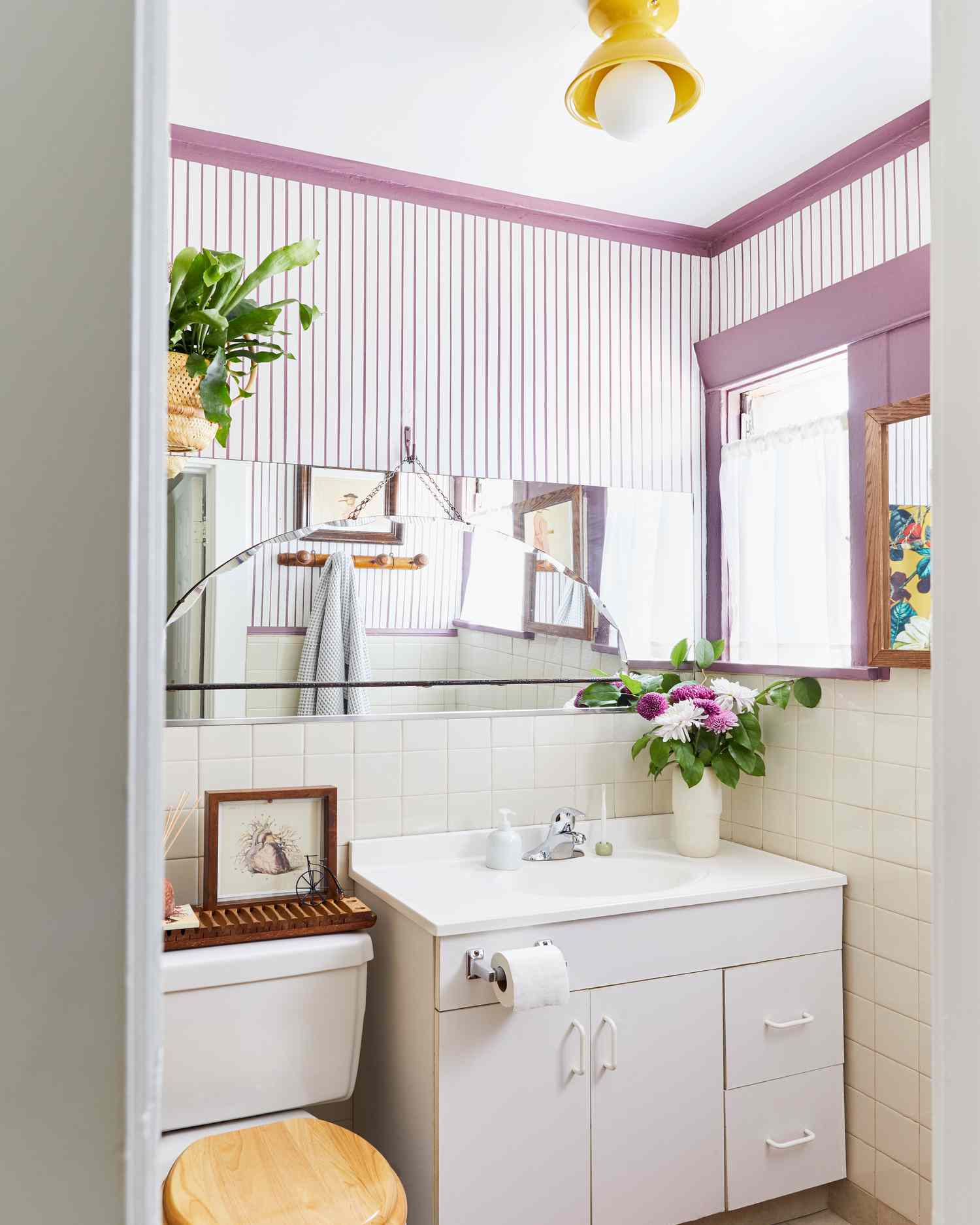 Petite salle de bain avec des rayures et des garnitures violettes.