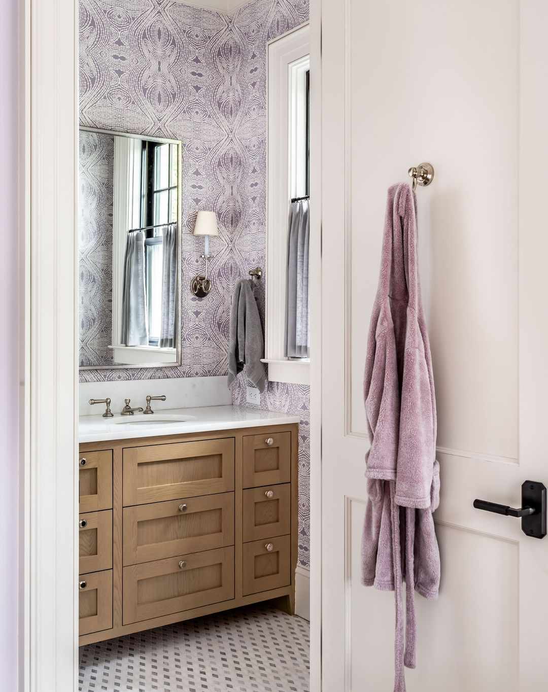 Banheiro sereno e calmo com papel de parede ornamentado em roxo e branco.