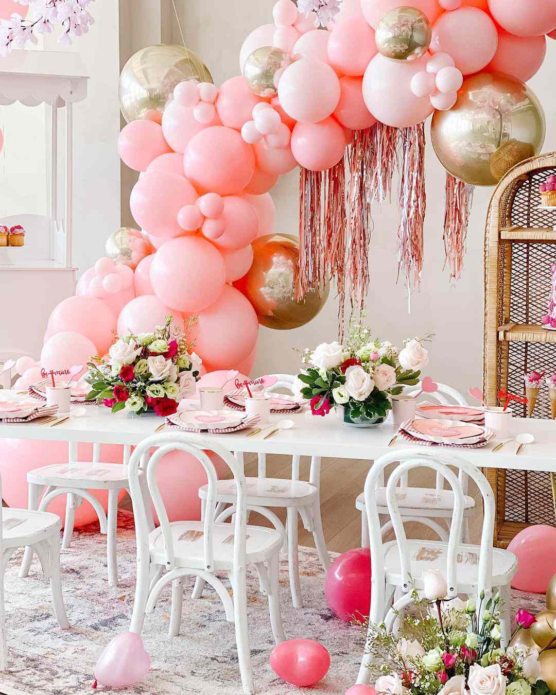 Arco de globos rosas y dorados sobre mesa blanca