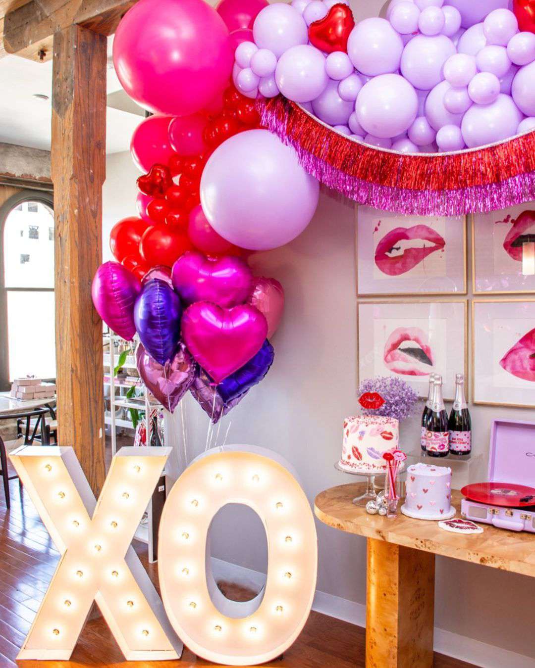 Pink and purple balloons over table and XO light