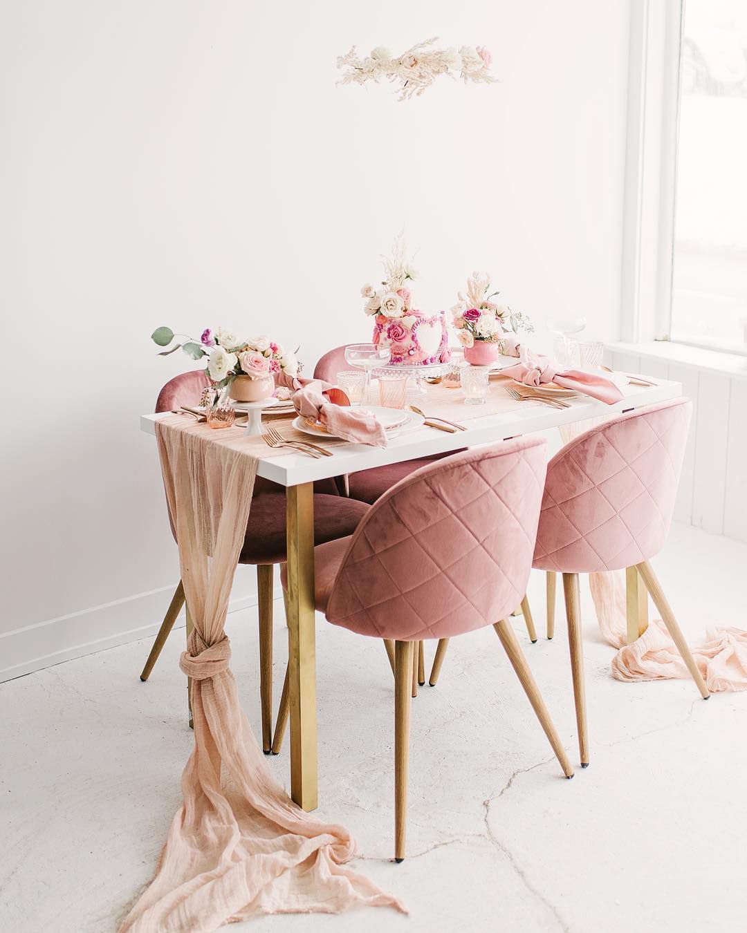 Sillas rosas alrededor de mesa blanca y camino de mesa rosa