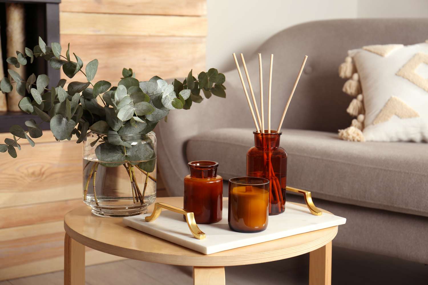 Ramas de eucalipto, ambientador aromático de juncos y velas sobre mesa de madera en salón. Elemento de interior