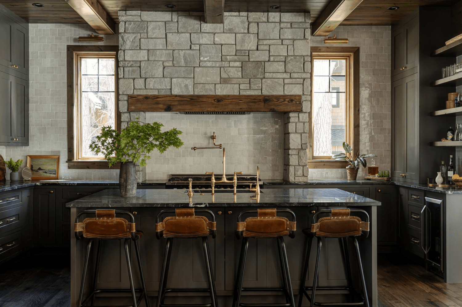 Küche mit dunklen Schränken und Arbeitsplatten, rustikalen Holzakzenten und einer Steinwand