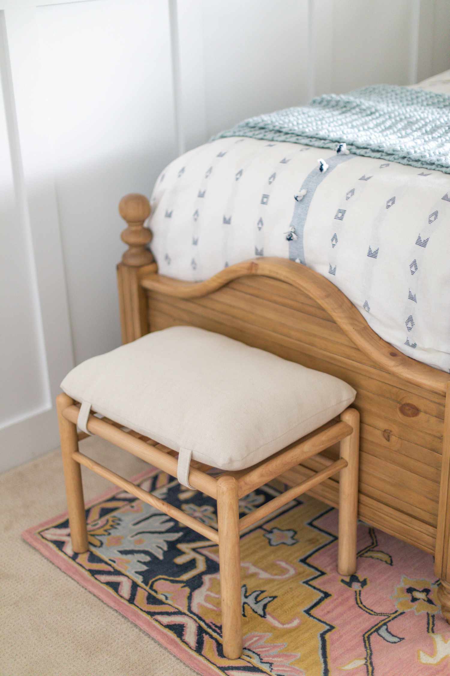 Chambre à coucher avec literie bleu clair et blanc et un tapis rose coloré