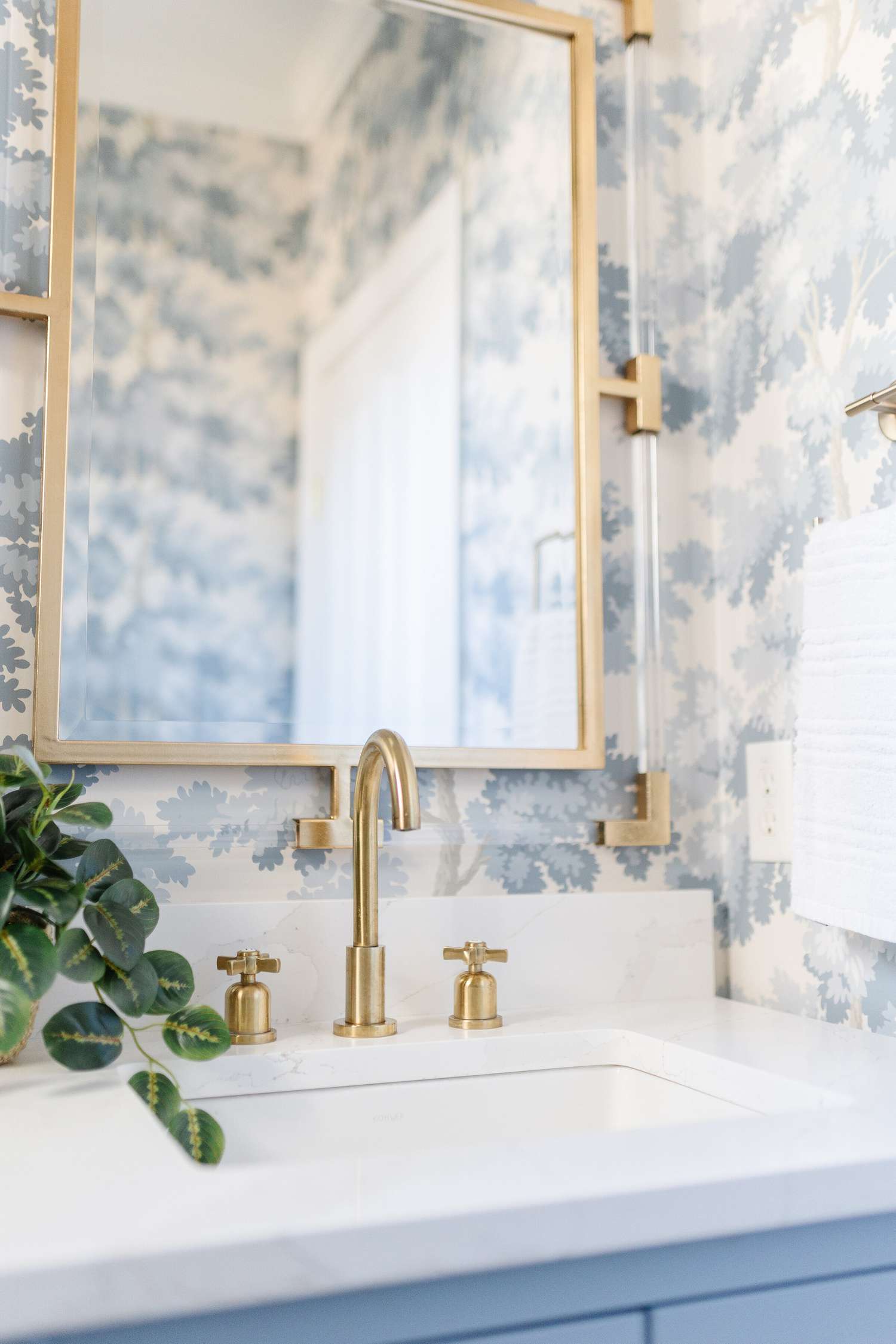 Salle de bain avec papier peint bleu clair et blanc et accents en laiton