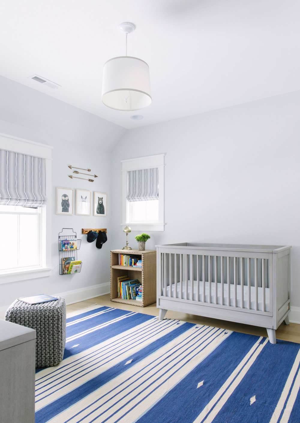Quarto de bebê com paredes azuis claras e tapete listrado azul mais escuro