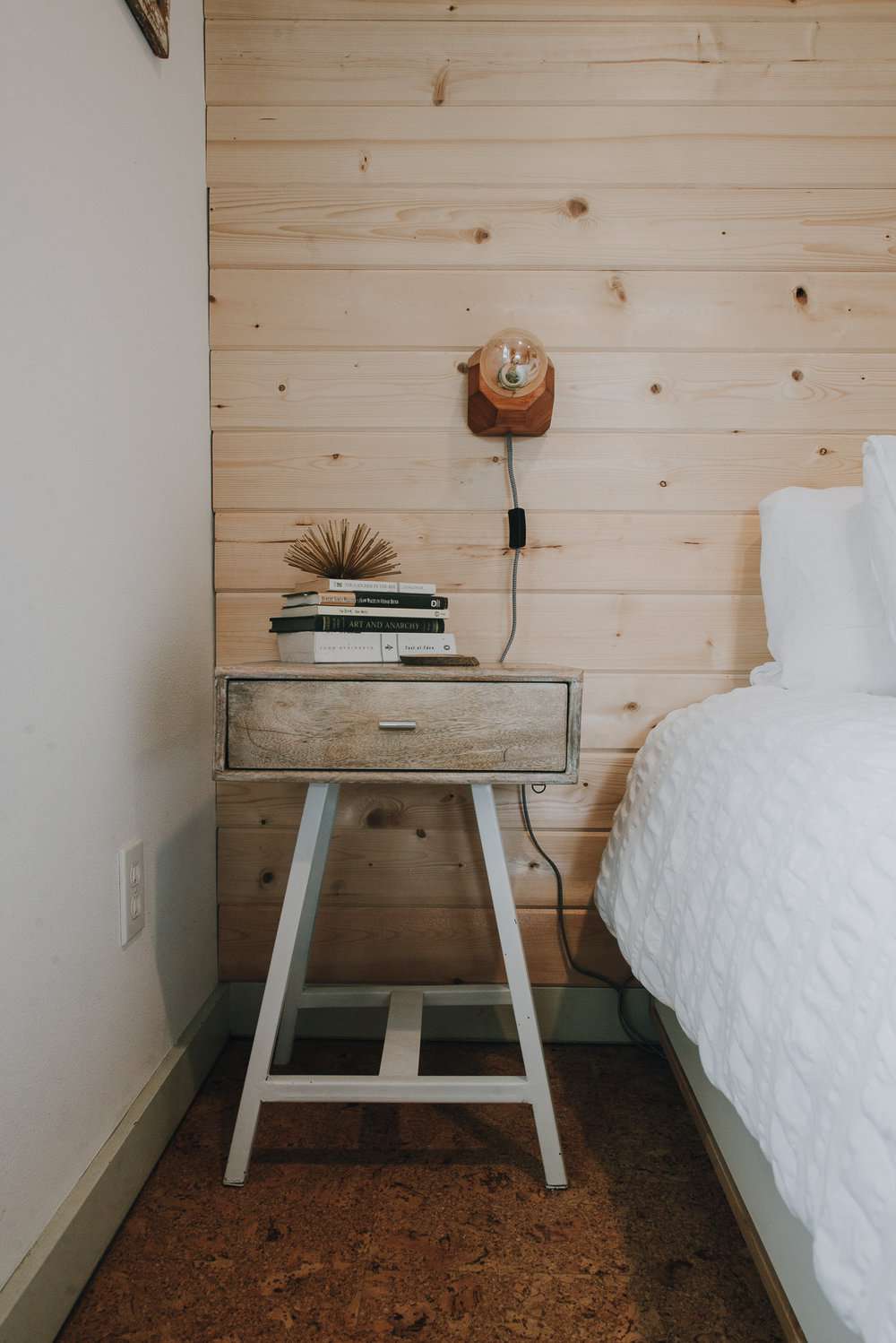 Parede de acento de shiplap de madeira de pinho natural atrás de uma cama e de uma mesinha de cabeceira