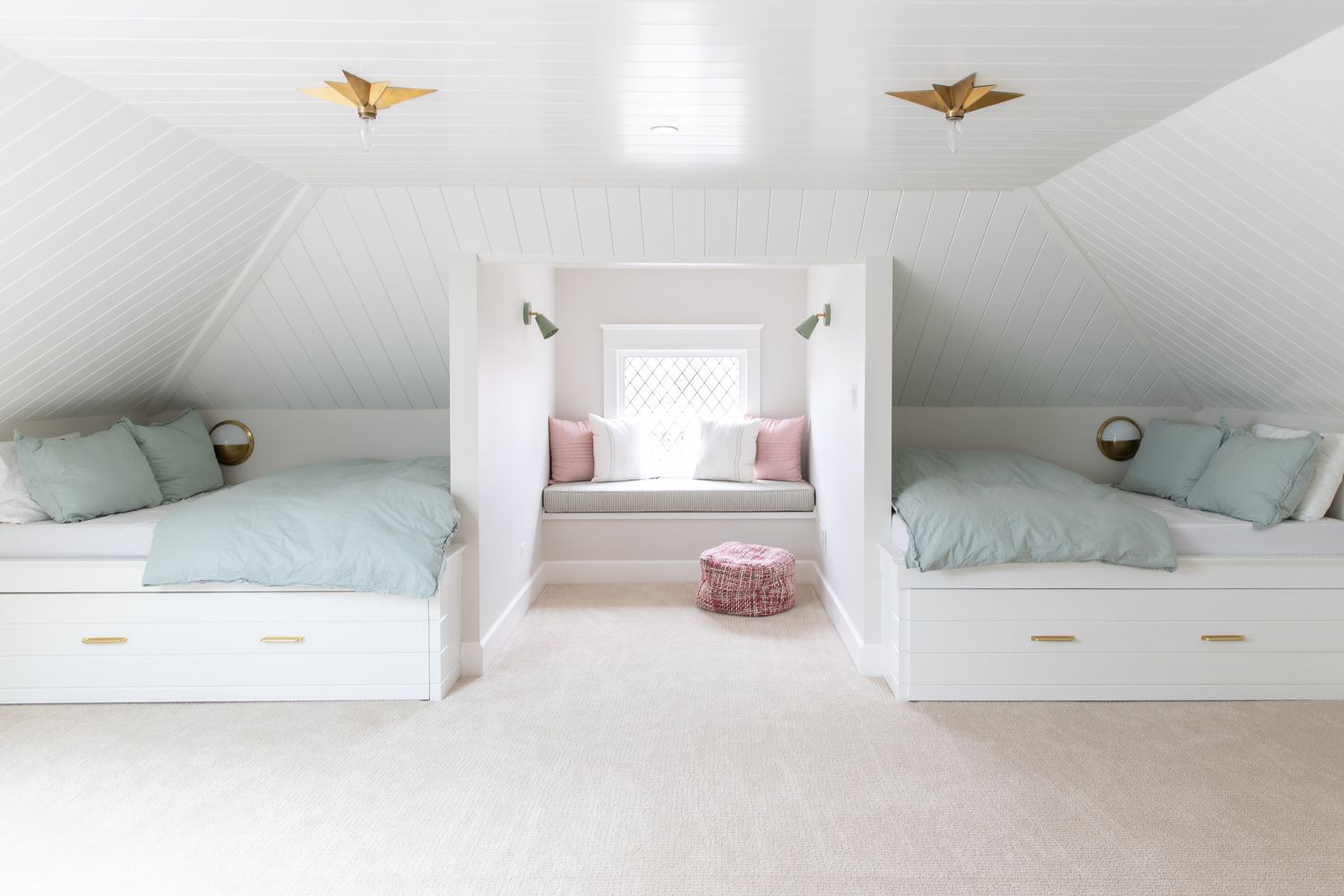 Dormitorio abuhardillado blanco con camas empotradas, un rincón con ventana de lectura y paredes y techo de shiplap