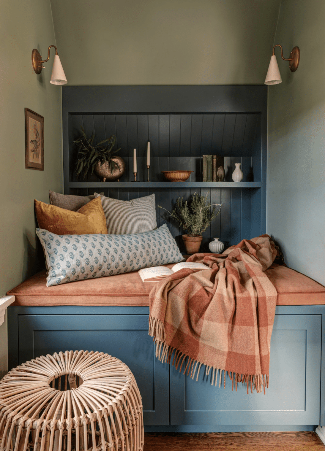 Rincón de dormitorio con un acogedor asiento y fondo de shiplap azul oscuro con una pequeña estantería