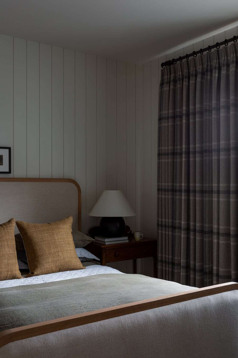 Shiplap blanco instalado verticalmente en un dormitorio con cortinas de cuadros escoceses