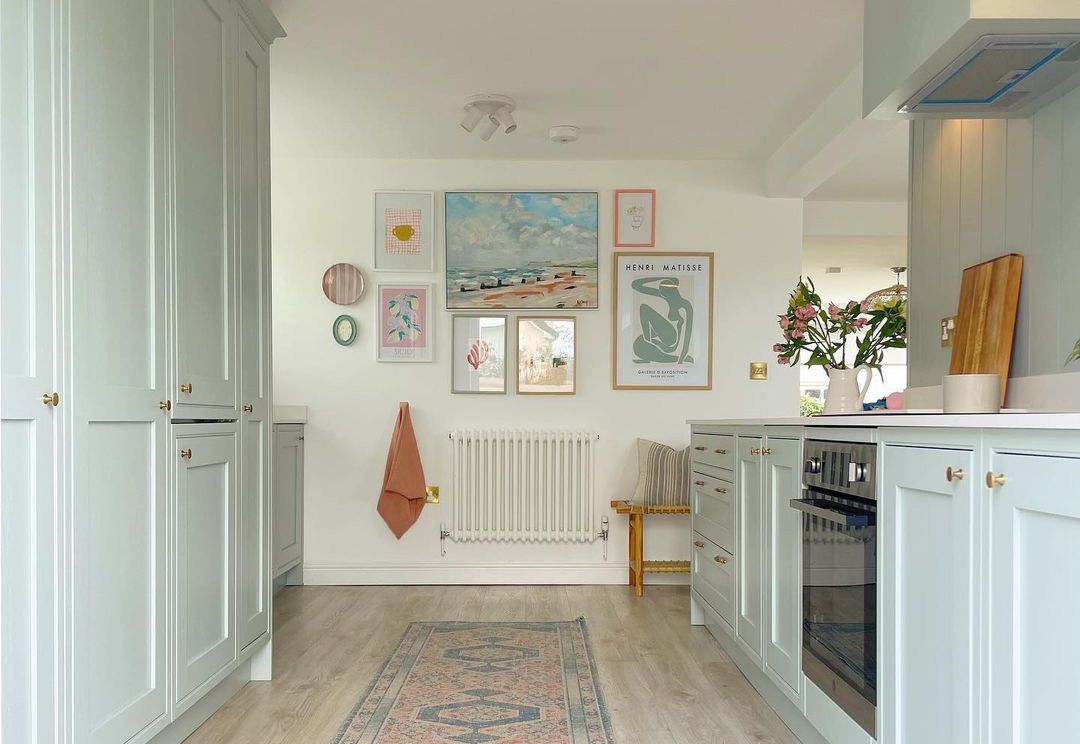 Hellblaue kleine Pantry-Küche mit pastellfarbener Galeriewand