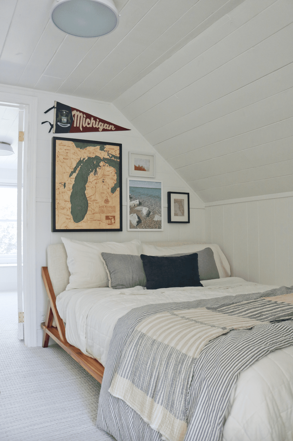 Canto de quarto em shiplap branco com uma cama e uma parede de galeria acima dela